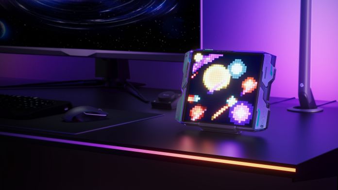 A colorful pixelated light display featuring space-themed graphics sits on a gaming desk, illuminated by ambient lighting.