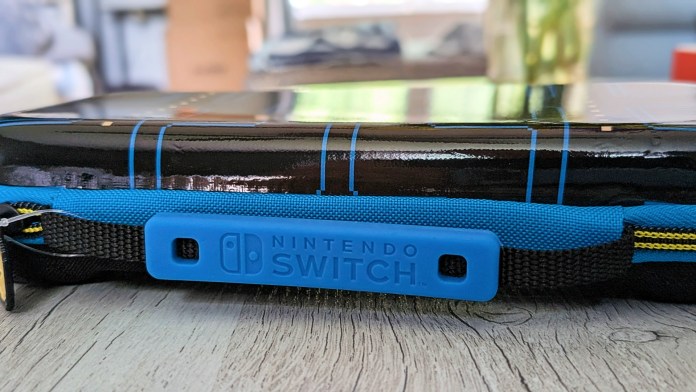 Close-up view of the side of a PowerA Pac-Man Protection Case for Nintendo Switch, featuring a blue strap labeled 'NINTENDO SWITCH' and a glossy black surface with blue accents.