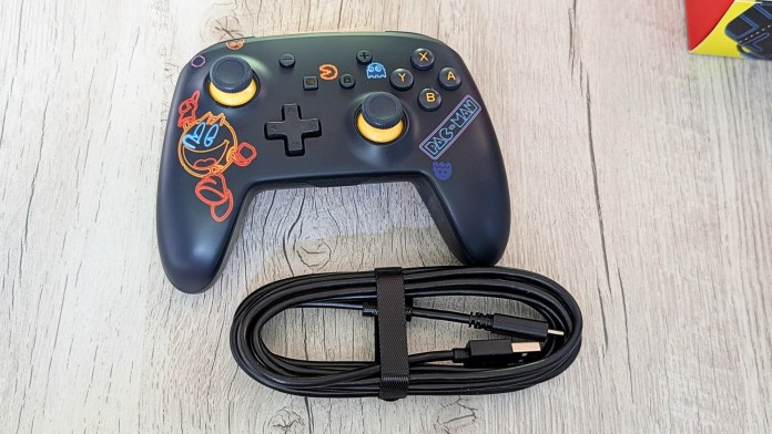 PowerA PAC-MAN Neon Arcade Controller for Nintendo Switch featuring colorful LED lighting and ergonomic design, accompanied by a USB-C charging cable.