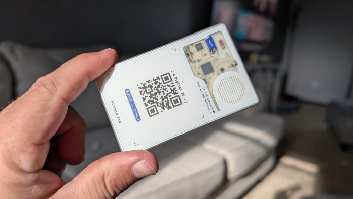 A person holding the Rolling Square AirCard Pro Bluetooth tracker, showcasing its sleek design and QR code features against a blurred background.