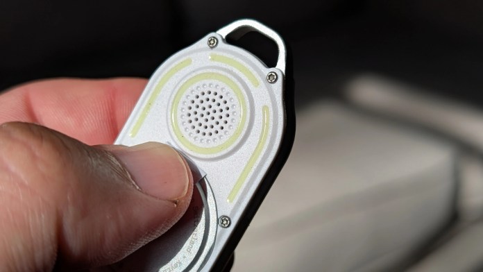 Close-up of a person's hand holding the Rolling Square AirNotch Pro Bluetooth tracker, showcasing its sleek design and speaker grill.