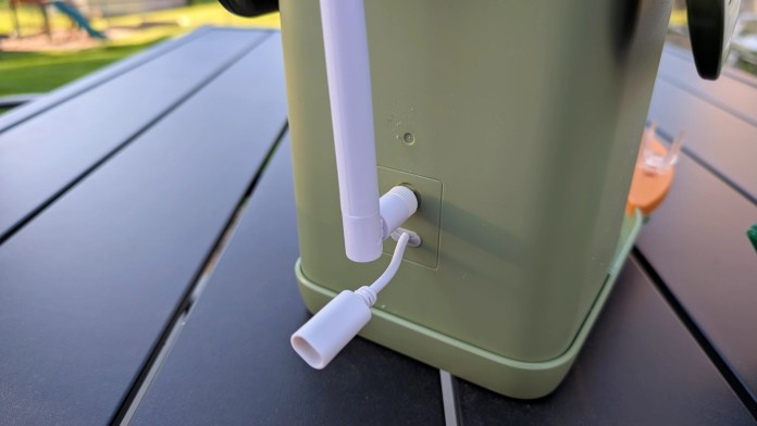 Close-up view of the connection ports on the back of the Vinguys Smart Bird Feeder, showing a white cable and the feeder's green exterior.
