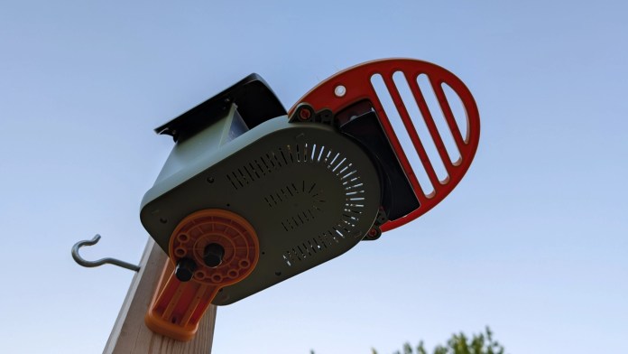 Close-up view of the Vinguys Smart Bird Feeder V-Feeder mounted on a pole, showcasing its sleek design and solar-powered features against a clear sky.