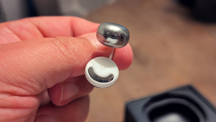 Close-up of a person holding Joyroom JR-OE3 Open-Ear Earbuds, highlighting their sleek design and features.