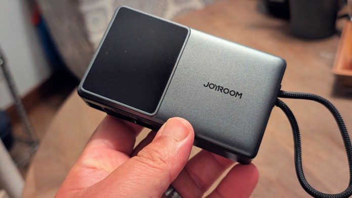 A person holding a Joyroom JR-PR1 Retractable Power Bank, showcasing its compact design and built-in retractable cable.