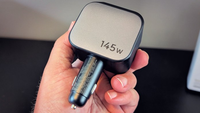 A person holding the UGREEN Nexode Retractable 145W Car Charger, showcasing its compact design and power rating.