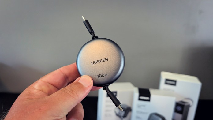 UGREEN Nexode Retractable USB-C Cable 100W held in a person's hand, showcasing its compact design with retractable features.