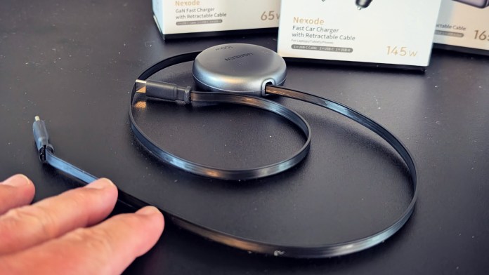 UGREEN Nexode 145W car charger with retractable cable, showcasing a sleek design and a hand pressing the cable.