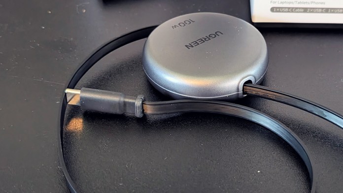 A close-up view of the UGREEN Nexode Retractable USB-C Cable 100W showing its retractable design, with the cable partially extended from a round case.