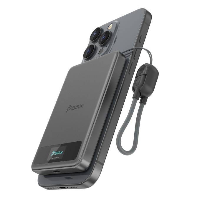 A SolidSafe power bank from BMX is shown charging a smartphone. The power bank features a sleek design with a USB-C lanyard cable and a color LCD display to monitor battery percentage.