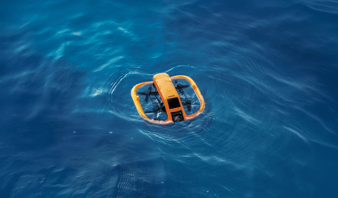 An aerial view of the HOVERAir AQUA, a waterproof self-flying camera, floating on calm blue water.