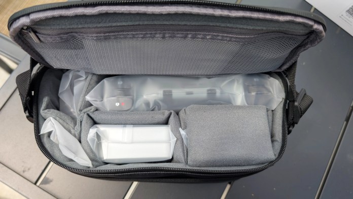 An open drone carrying case, featuring compartments for the Potensic ATOM 2 drone, batteries, and accessories, all organized with gray fabric lining.
