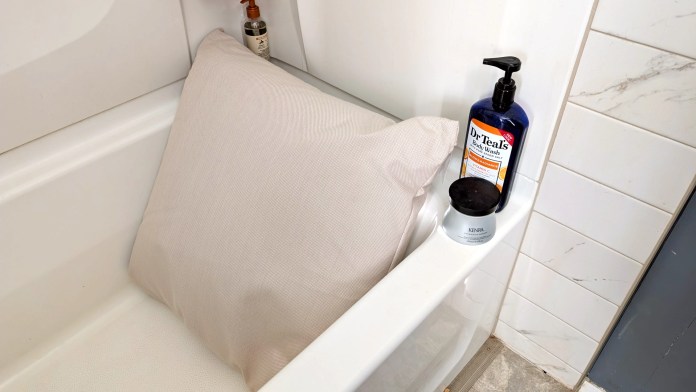 A cozy bath with BADESOFA Back Bath Pillow positioned in the tub, accompanied by Dr. Teal's Body Wash and a skincare product on the edge.