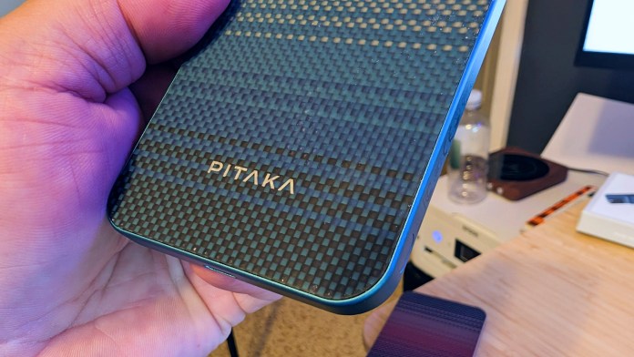 A close-up of the PITAKA Aramid Fiber Magnetic Power Bank held in a hand, showcasing its textured surface and logo.