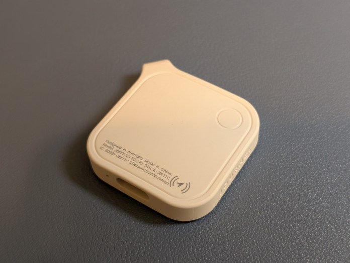 A LOC8 Finder Fob 2 Universal tracking device is shown on a textured gray surface. The device is rectangular with rounded edges, and features a small button and a port for charging.