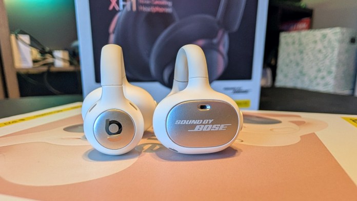 Close-up of two pairs of Baseus Inspire XH1 headphones and XC1 earbuds, showcasing their design with visible branding elements 'b' and 'SOUND BY BOSE' on a tabletop.