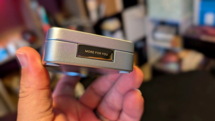 A close-up of a hand holding a UGREEN MagFlow 3-in-1 Magnetic Wireless Charger, showcasing its sleek design and the engraving 'MORE FOR YOU' on the side.