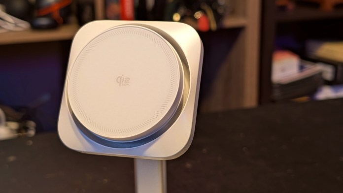 Close-up view of the ESR CryoBoost Magnetic Charging Station, featuring a sleek, circular design with Qi2 logo, set against a blurred background of tech accessories.