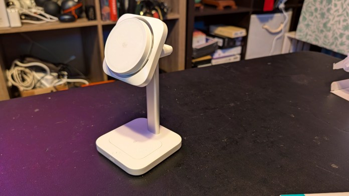 A white ESR CryoBoost 3-in-1 Magnetic Charging Station on a black desk, designed to charge an iPhone, Apple Watch, and AirPods simultaneously.