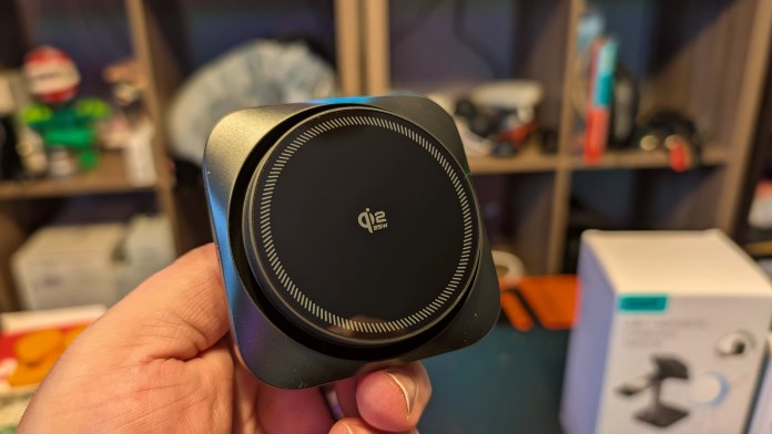 A person holding the ESR OmniLock Magnetic Car Charger with a sleek black design in a home setting.