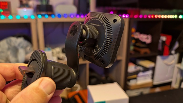 Close-up of the ESR OmniLock Magnetic Car Charger, featuring a sleek design and adjustable mounting mechanism, with a blurred background showing a colorful LED-lit environment.