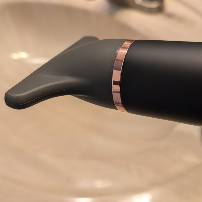 Close-up of a black hairdryer nozzle with a rose gold accent.