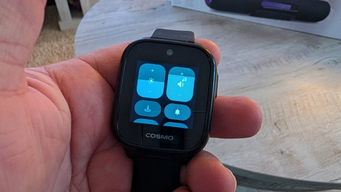 A person holding a smartwatch displaying an interface with various icons, including controls for brightness, volume, and notifications.