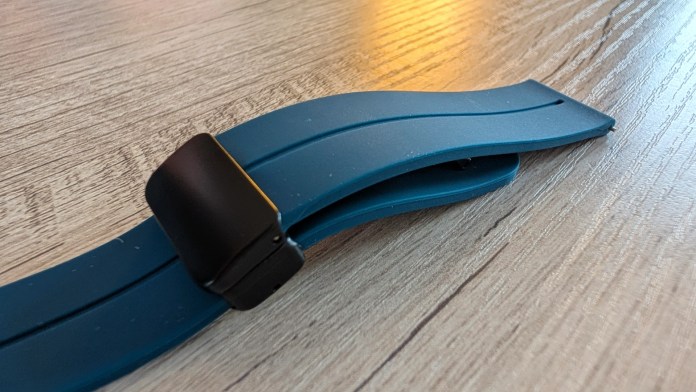 Close-up of a blue silicone wristband with a black clasp resting on a wooden surface.