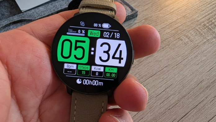 A close-up of a smartwatch displaying fitness data, including time (05:34), date (02/18), battery percentage (88%), steps (15), calories (0), and distance (0.00 km), held in a person's hand.