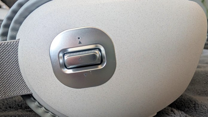 Close-up of a control panel on a headset with a toggle switch and adjustment buttons.