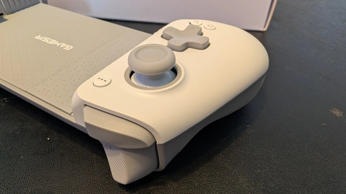 Close-up of a grey gaming controller featuring a thumbstick and various buttons.