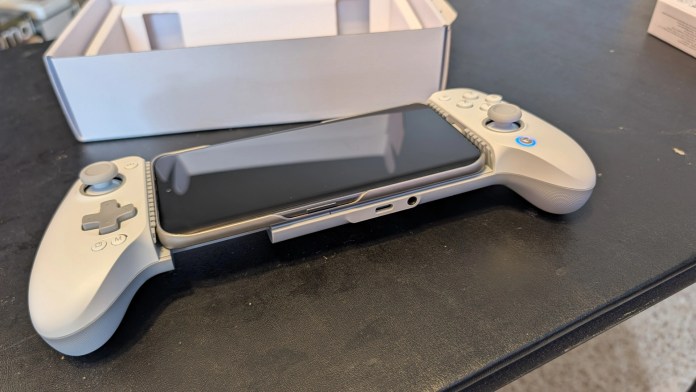 A smartphone placed inside a white game controller, with a small box visible in the background.