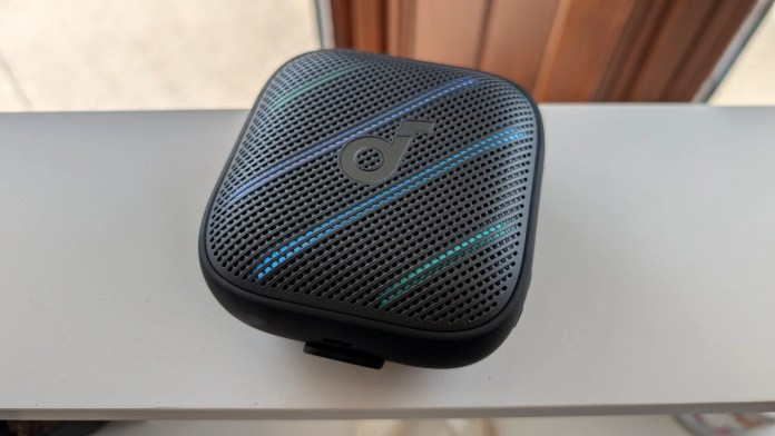 A portable Bluetooth speaker with a textured surface and blue LED accents, resting on a white surface.