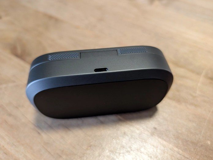 A black electronic device with a USB-C port, viewed from an angle revealing its flat underside and textured top edge.