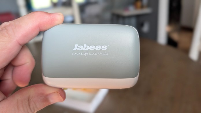 A person holding a Jabees wireless earbuds charging case with the logo and tagline 'Love Life Love Music' visible.
