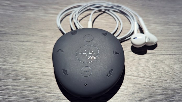 A black audio device with control buttons, labeled 'mophie zen', accompanied by white earphones on a wooden surface.