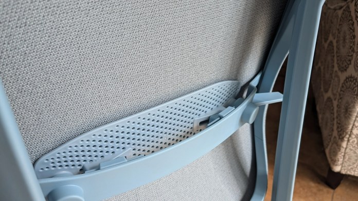 Close-up of the back of a light blue chair, showcasing its textured fabric and flexible support structure.