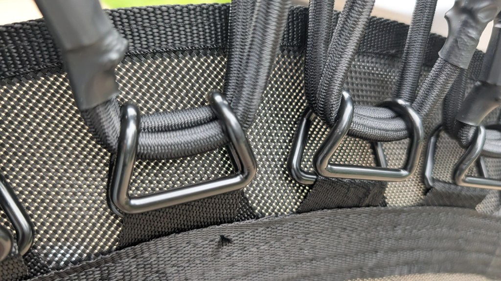 Close-up of black fabric with metal D-rings and woven straps, showcasing a durable design.