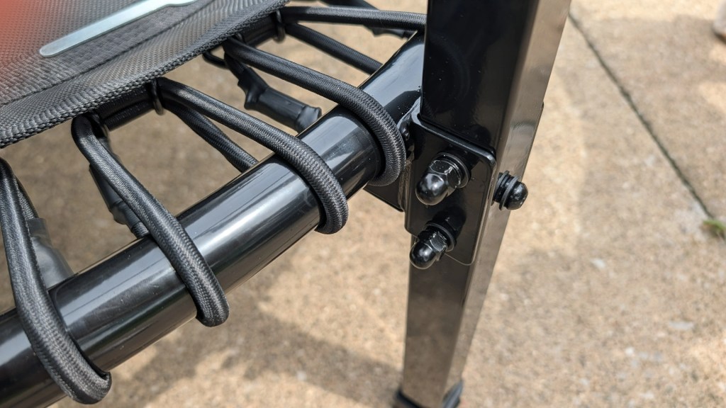 Close-up view of the corner joint and elastic straps on a folding chair frame, highlighting the black metal structure and attachment details.