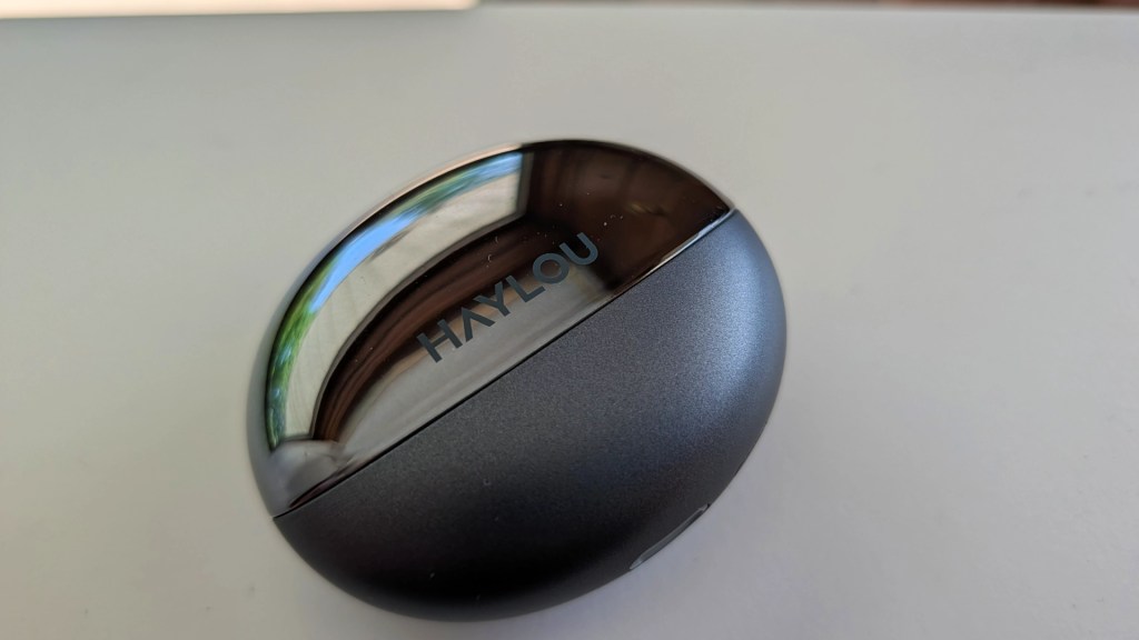 Close-up of a Haylou wireless earbuds charging case on a light surface.