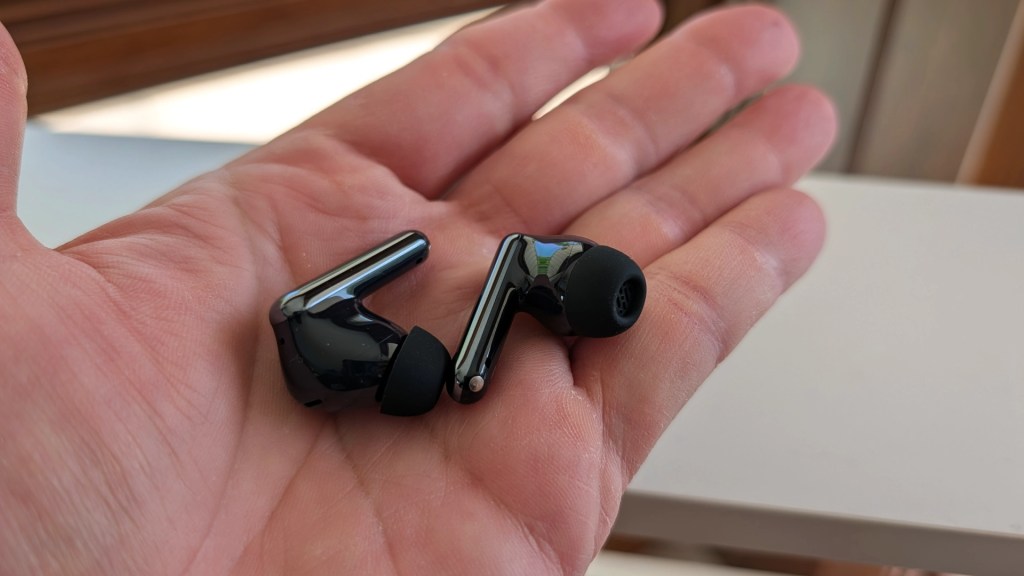 A black pair of wireless earbuds resting in an open palm, showcasing their sleek design and ear tips.