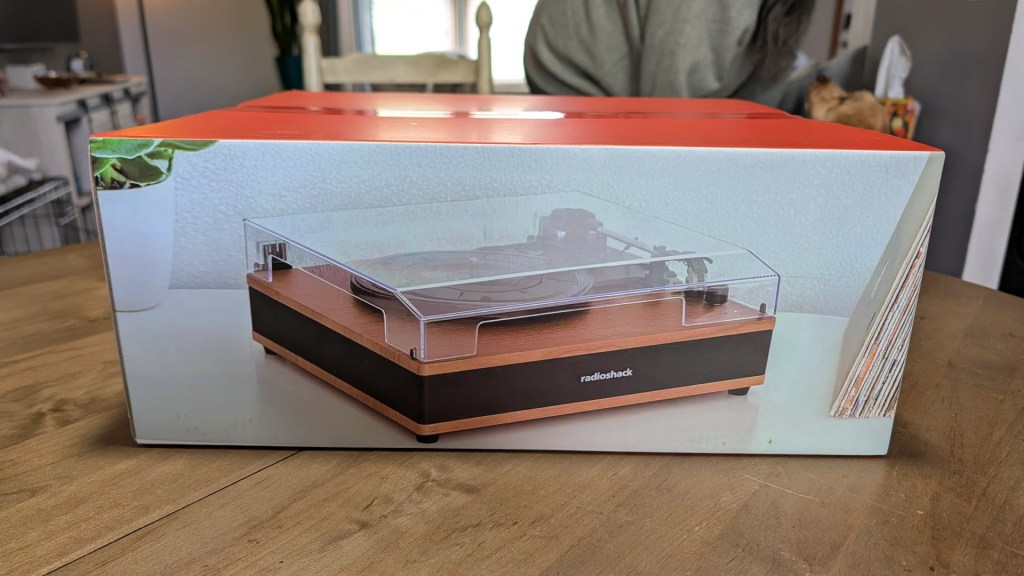 Box packaging of a turntable with a clear cover and wooden base, featuring the Radioshack logo.