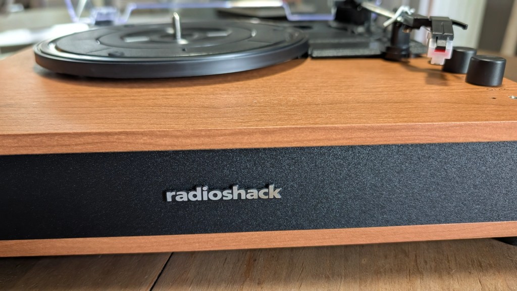 Close-up of a vintage-style turntable with a wooden finish, featuring a black platter and the 'radioshack' logo on the front.