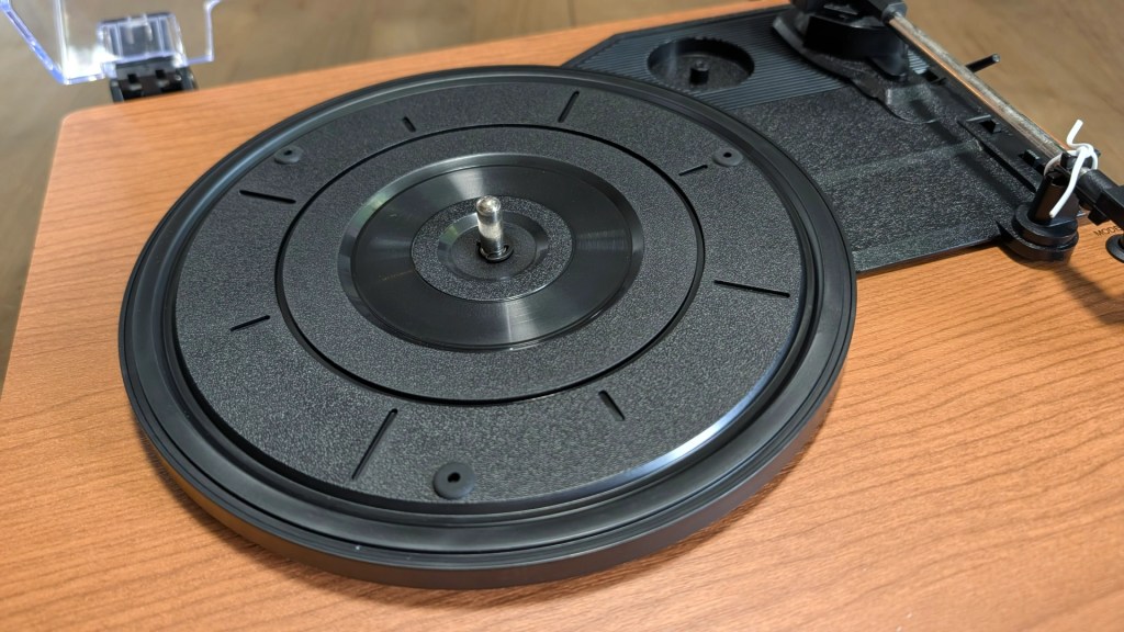 Close-up of a turntable platter on a wooden surface, showing the spindle and grooves designed for vinyl records.
