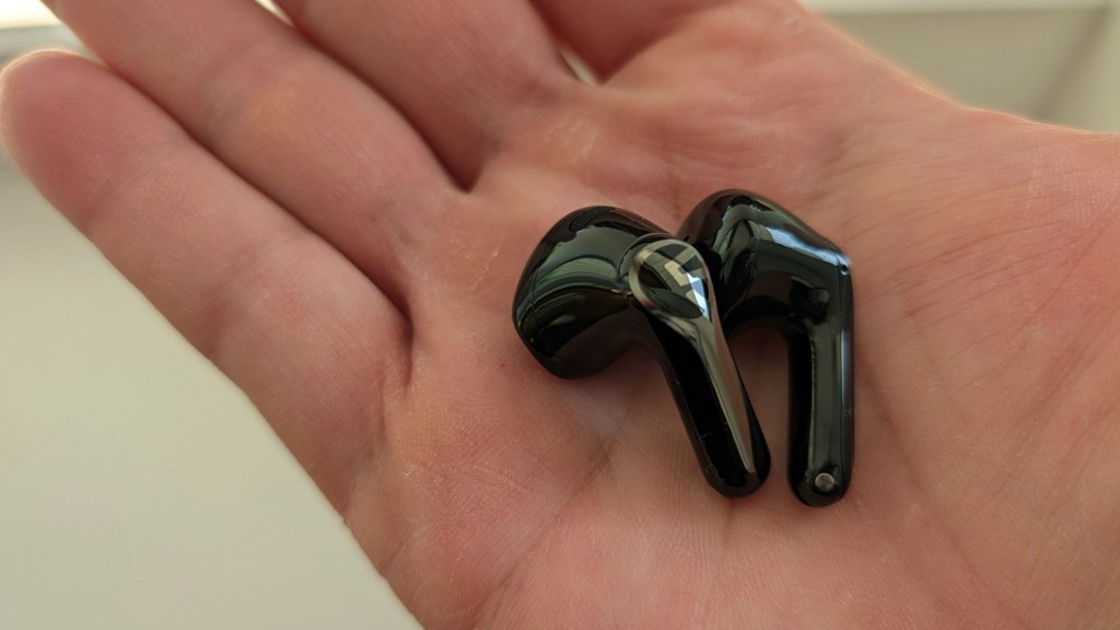 A pair of black wireless earbuds resting on a person's open palm.