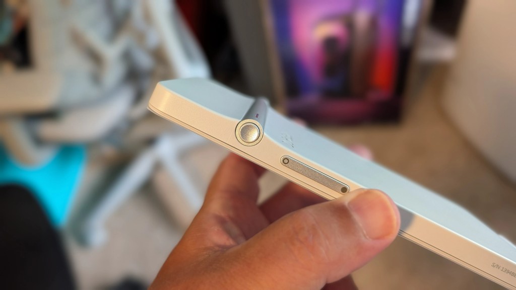 Close-up of a person's hand holding a sleek, modern smartphone from the side, showcasing the power button and volume controls.