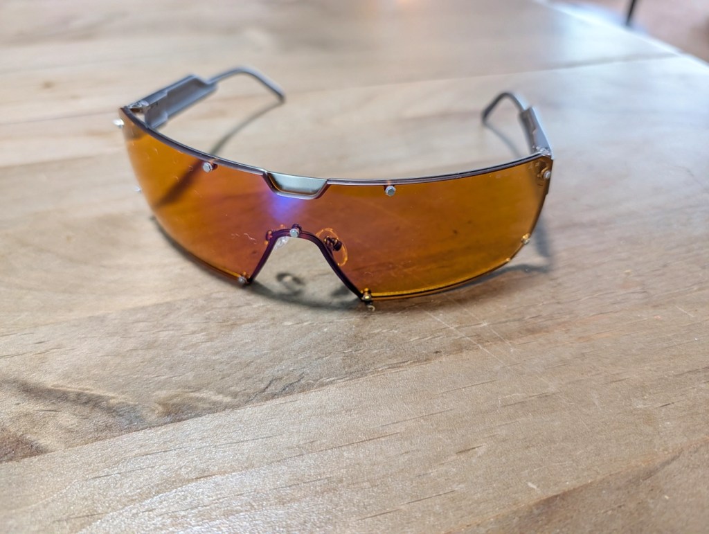 A pair of stylish amber-tinted sunglasses resting on a wooden surface.