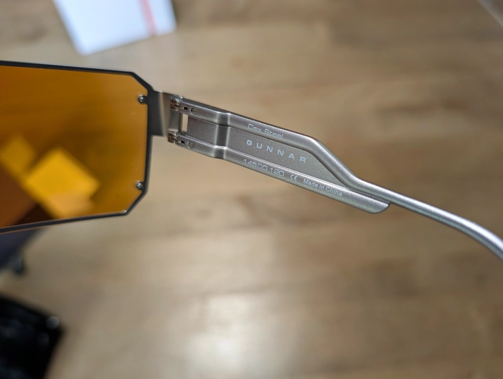 Close-up of Gunnar gaming glasses with amber lenses and metal frame, showing the hinge and branding details.