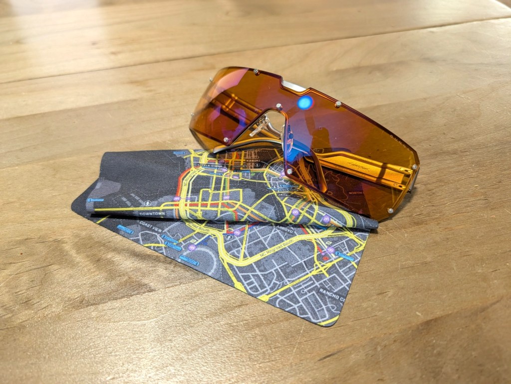 A pair of stylish sunglasses with brown lenses resting on a folded city map, alongside a pen, positioned on a wooden table.