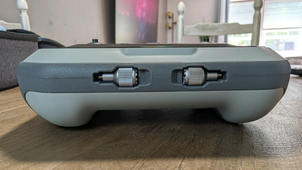 A close-up side view of a device with two knobs, set on a wooden table, showcasing its sleek design.